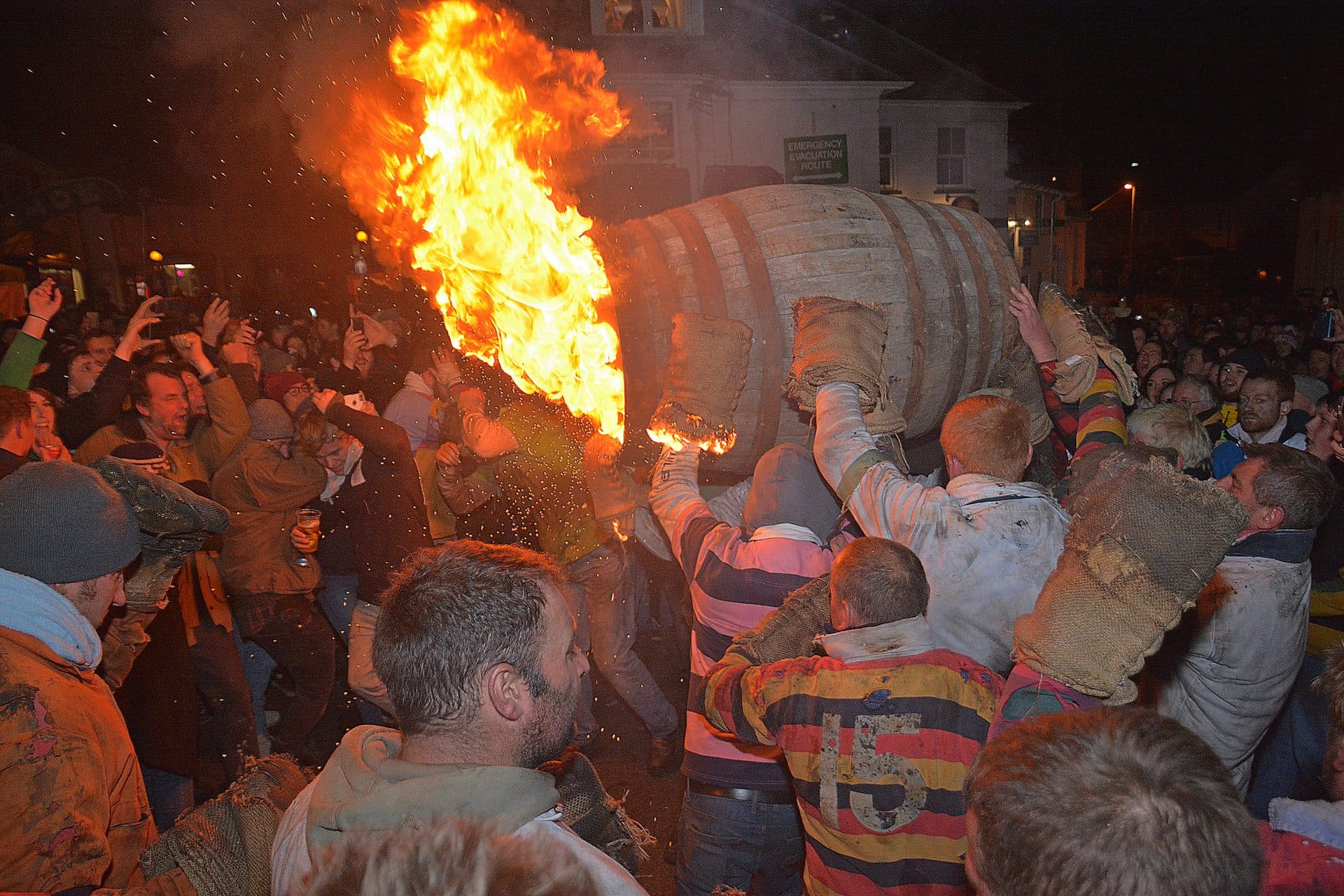 A flaming tar barrel carried on a man's shoulders through a packed crowd in Ottery St Mary
